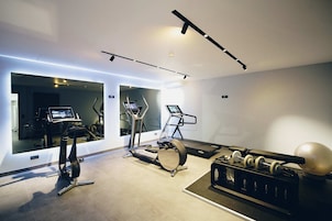 Un gimnasio moderno con equipo cardiovascular, máquinas de pesas y un espejo grande.