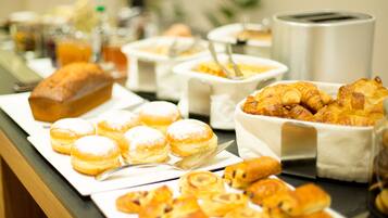 Ein Buffet mit verschiedenen Backwaren und Gebäck, darunter Croissants und Muffins, präsentiert auf Serviertabletts.