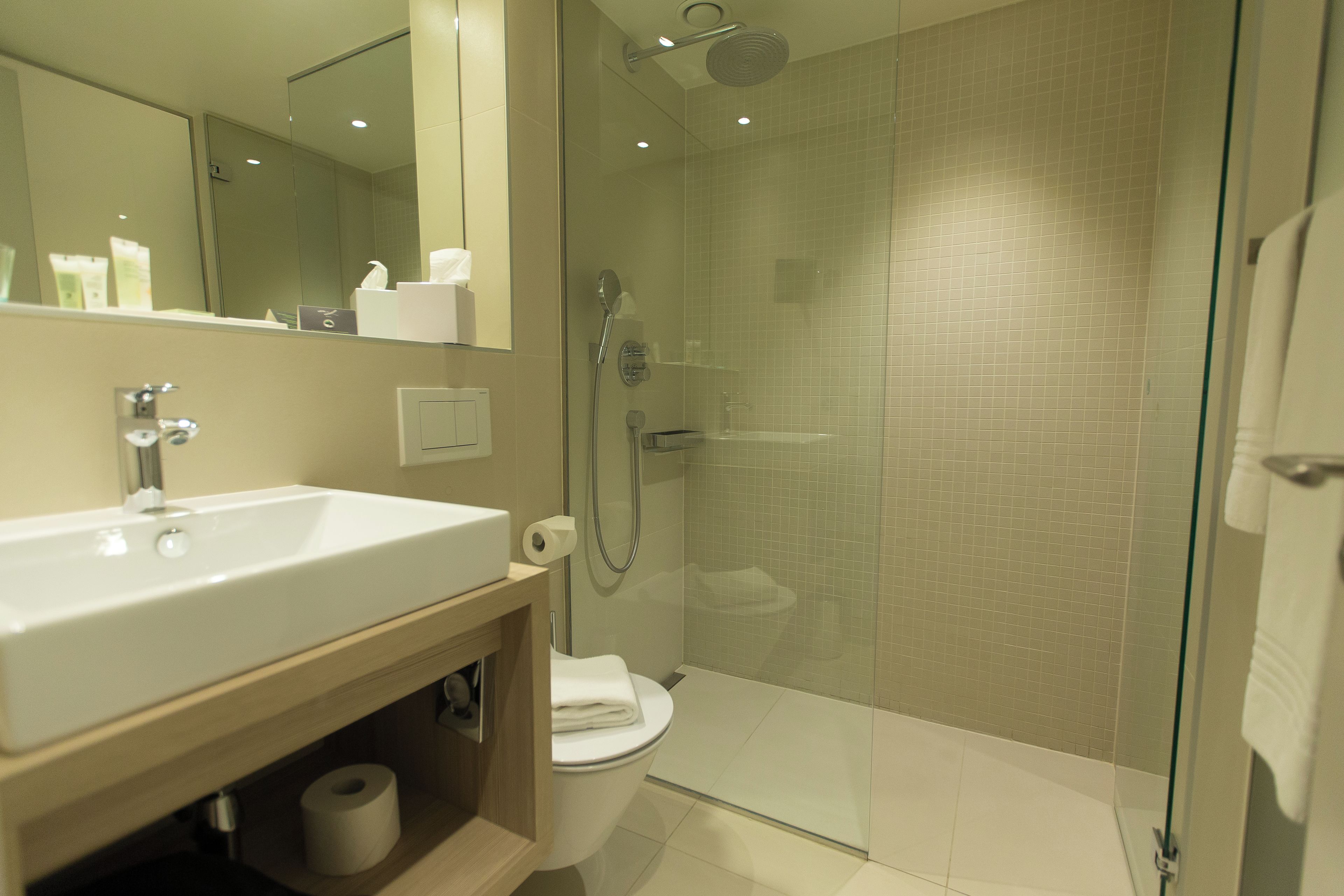 A modern bathroom with a glass-enclosed shower, a white sink, and a toilet.