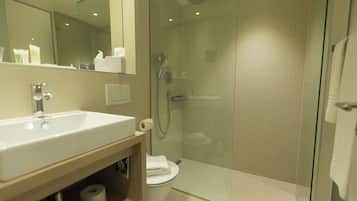 A modern bathroom with a glass-enclosed shower, a white sink, and a toilet.
