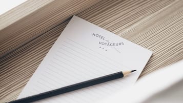 A hotel business card with the name 'Hôtel des Voyageurs' and a pencil on a wooden surface.