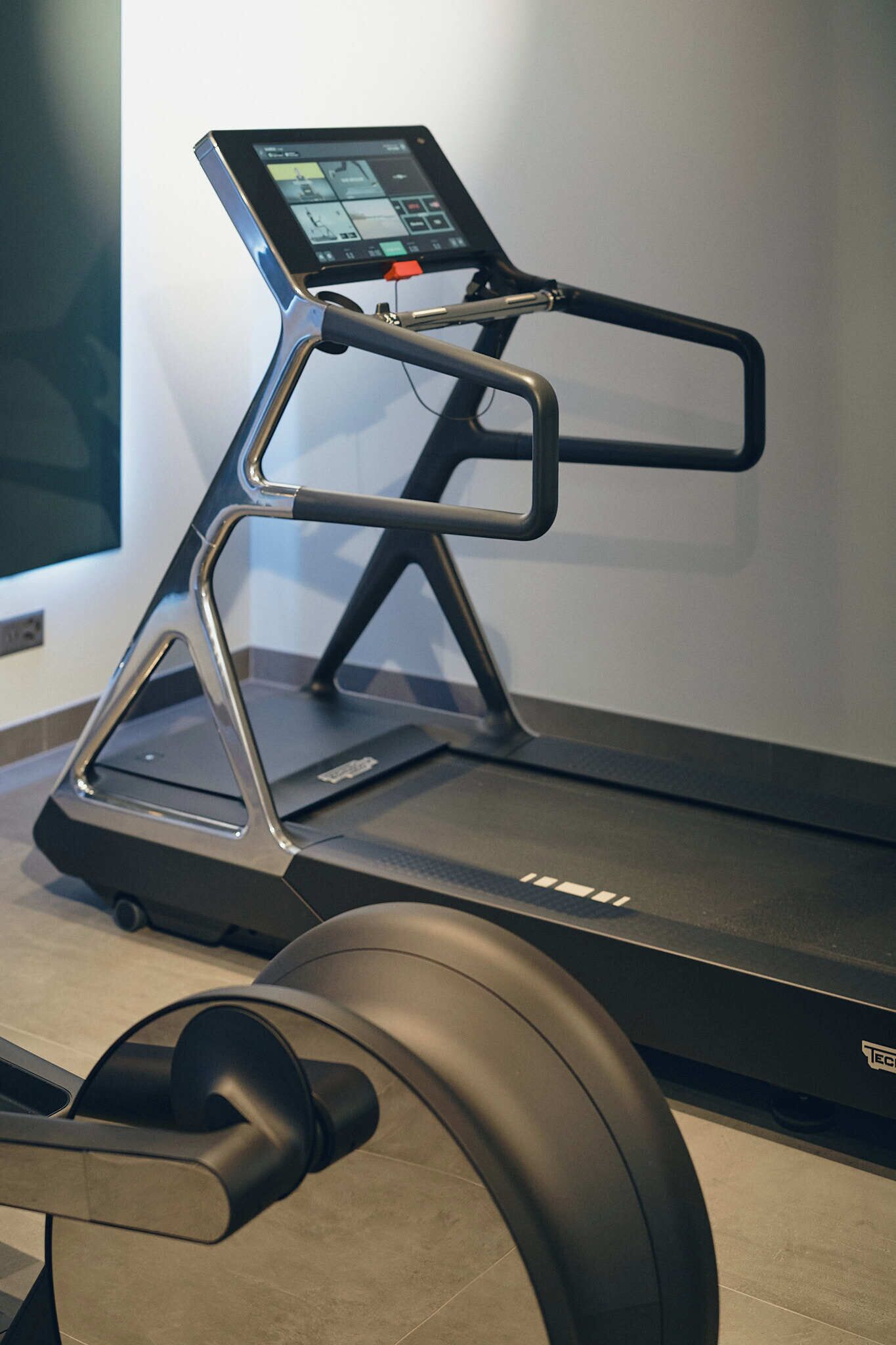 A treadmill with a digital display and a stationary bike in the foreground.