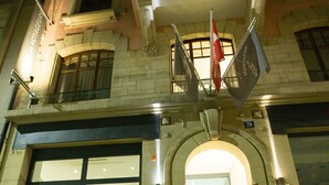 Un edificio con un'ampia vetrata, una scala ben visibile e un cartello sopra l'ingresso.