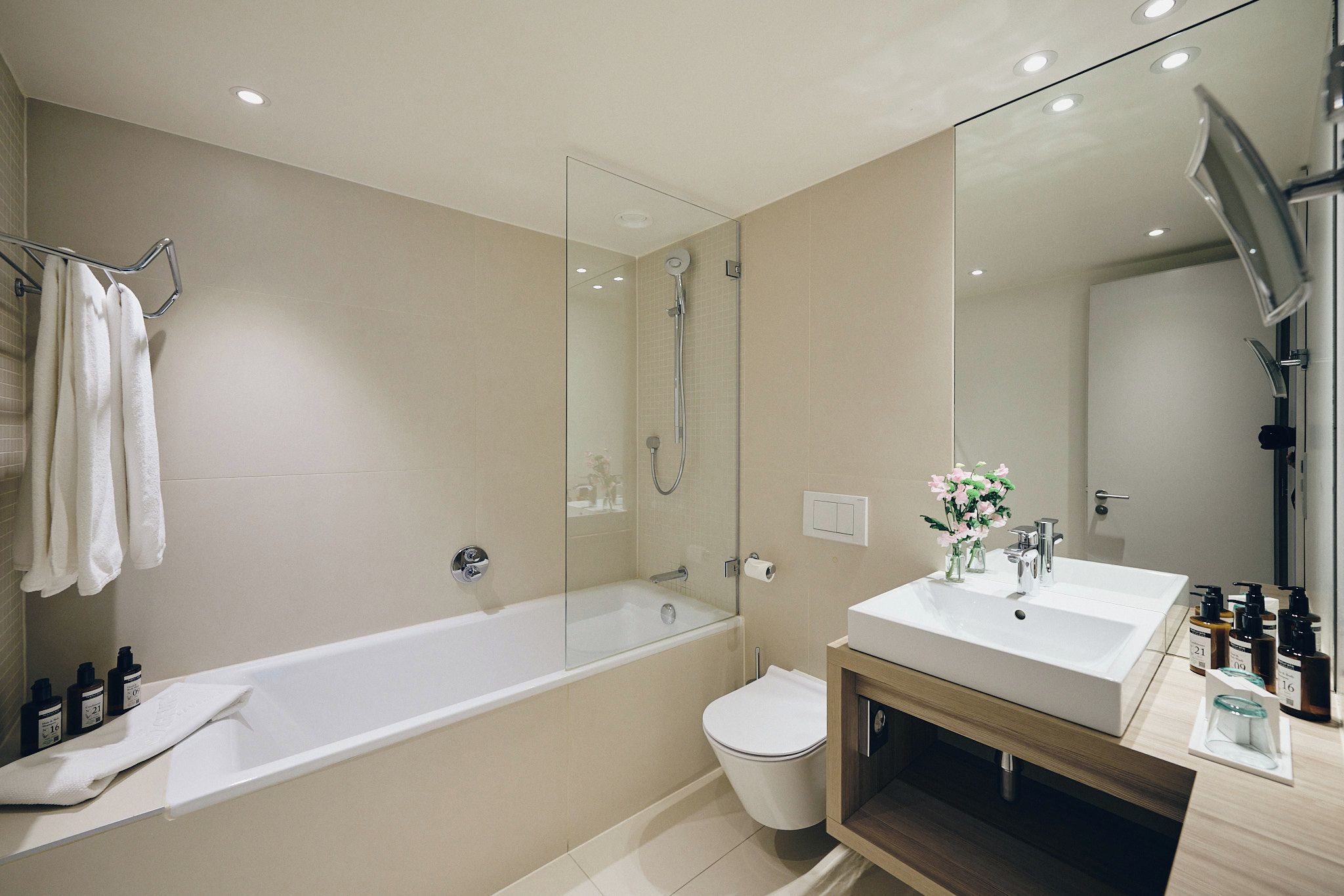 A modern bathroom with a bathtub, toilet, and vanity with a mirror.
