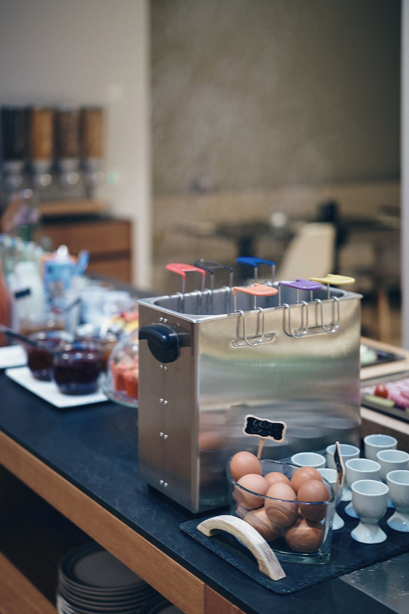 A kitchen counter with a coffee machine, a bowl of eggs, and a tray of cups.