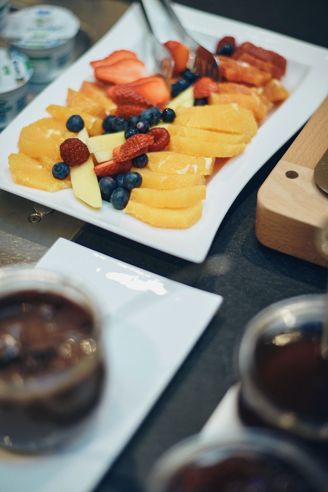 Un plato de fruta con fresas, arándanos y rodajas de naranja.
