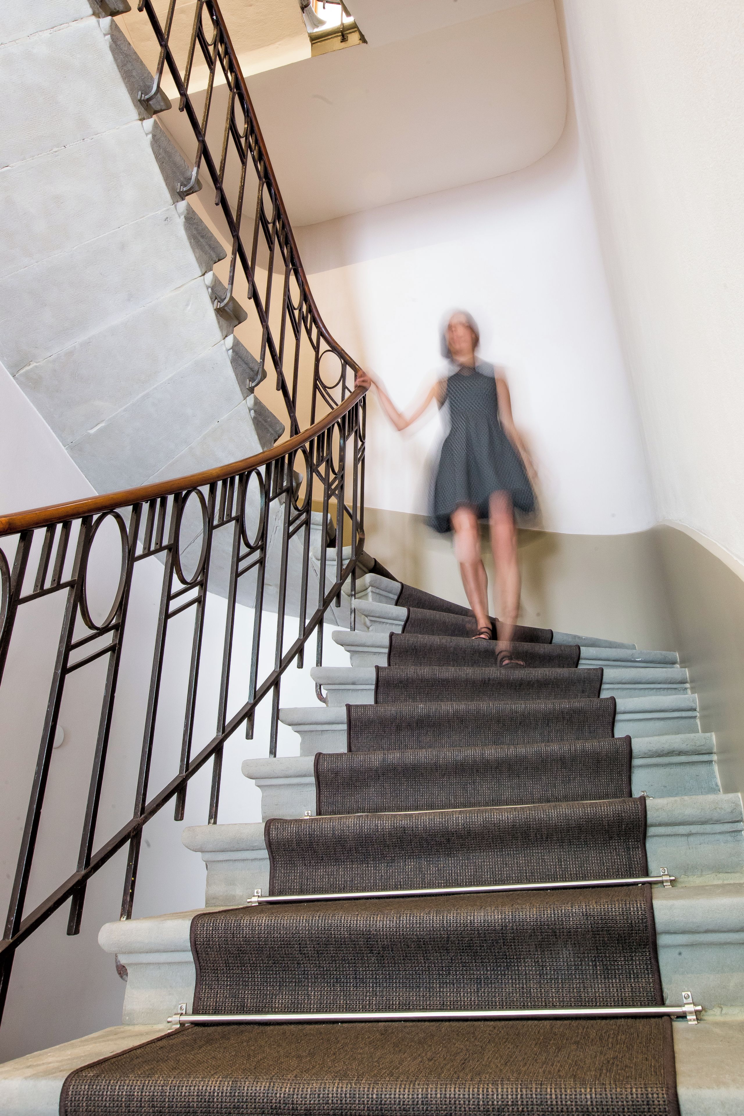 A staircase with a handrail and a person descending.