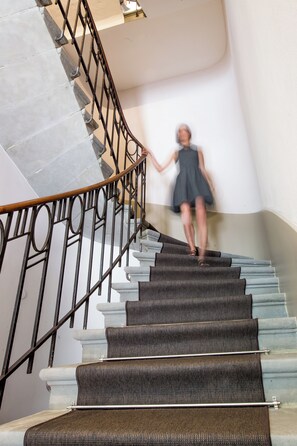 Un escalier avec une rampe et une personne qui descend.