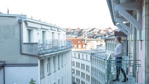 Un balcone con ringhiera in metallo che si affaccia su una vista urbana con numerosi edifici.