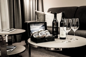 A hotel room with a round table displaying a wine bottle, two wine glasses, and a box of chocolates. - Hôtel des Voyageurs (Lausanne)