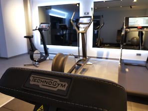 A gym with a treadmill, stationary bike, and elliptical machine.