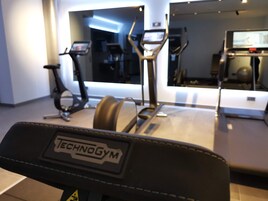 Un gimnasio con cinta de correr, bicicleta estática y máquina elíptica.
