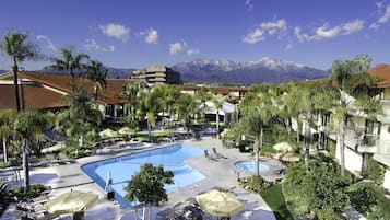 Un complexe hôtelier doté d’une piscine, de chaises longues et de palmiers.