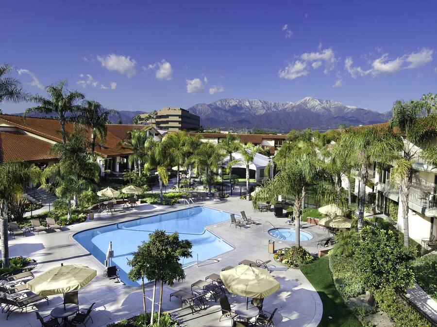A resort with a swimming pool, lounge chairs, and palm trees.