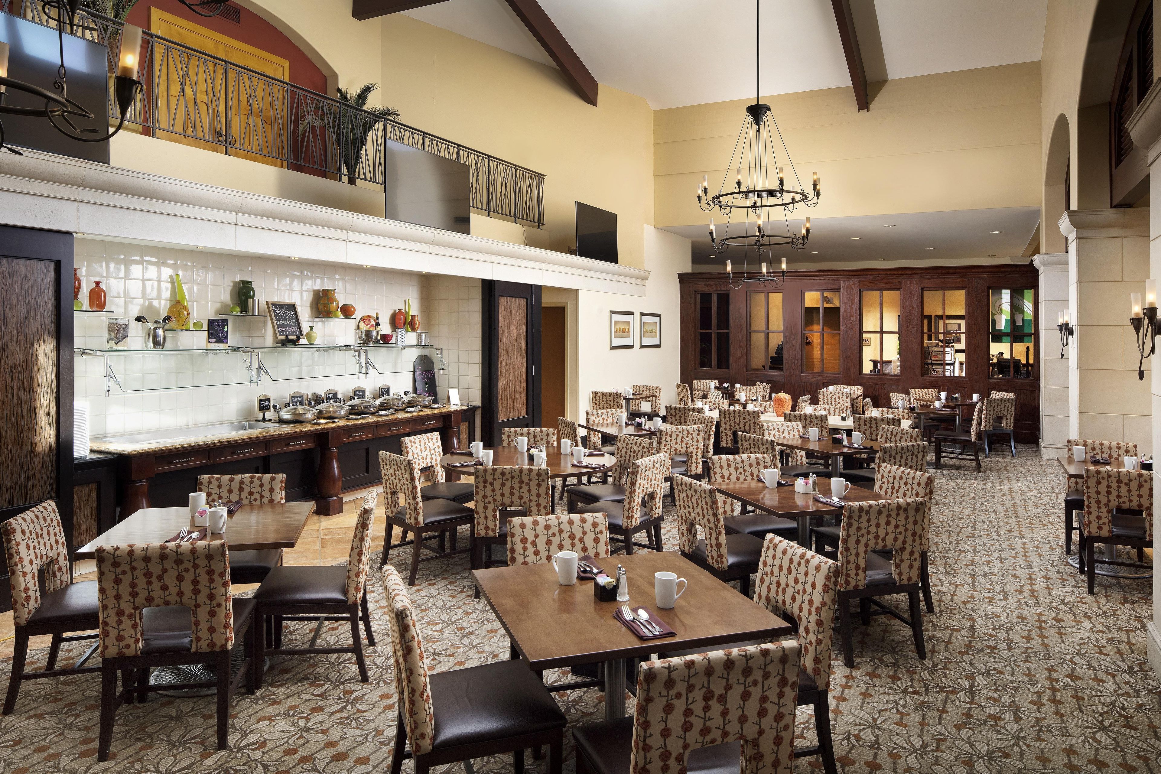 A spacious dining area with multiple tables and chairs, a kitchen area with various utensils and decorative items, and a balcony with a railing.