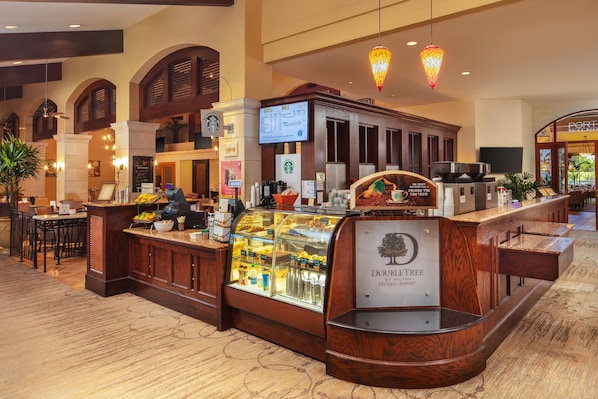 Vestíbulo de DoubleTree by Hilton Ontario Airport con una Starbucks, una presentación de alimentos y un área de descanso.