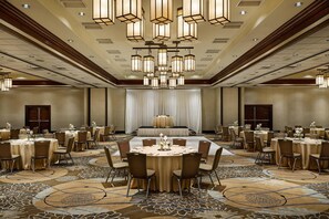 A large banquet hall with round tables, chairs, and a stage for presentations. - DoubleTree by Hilton Ontario Airport (Ontario)