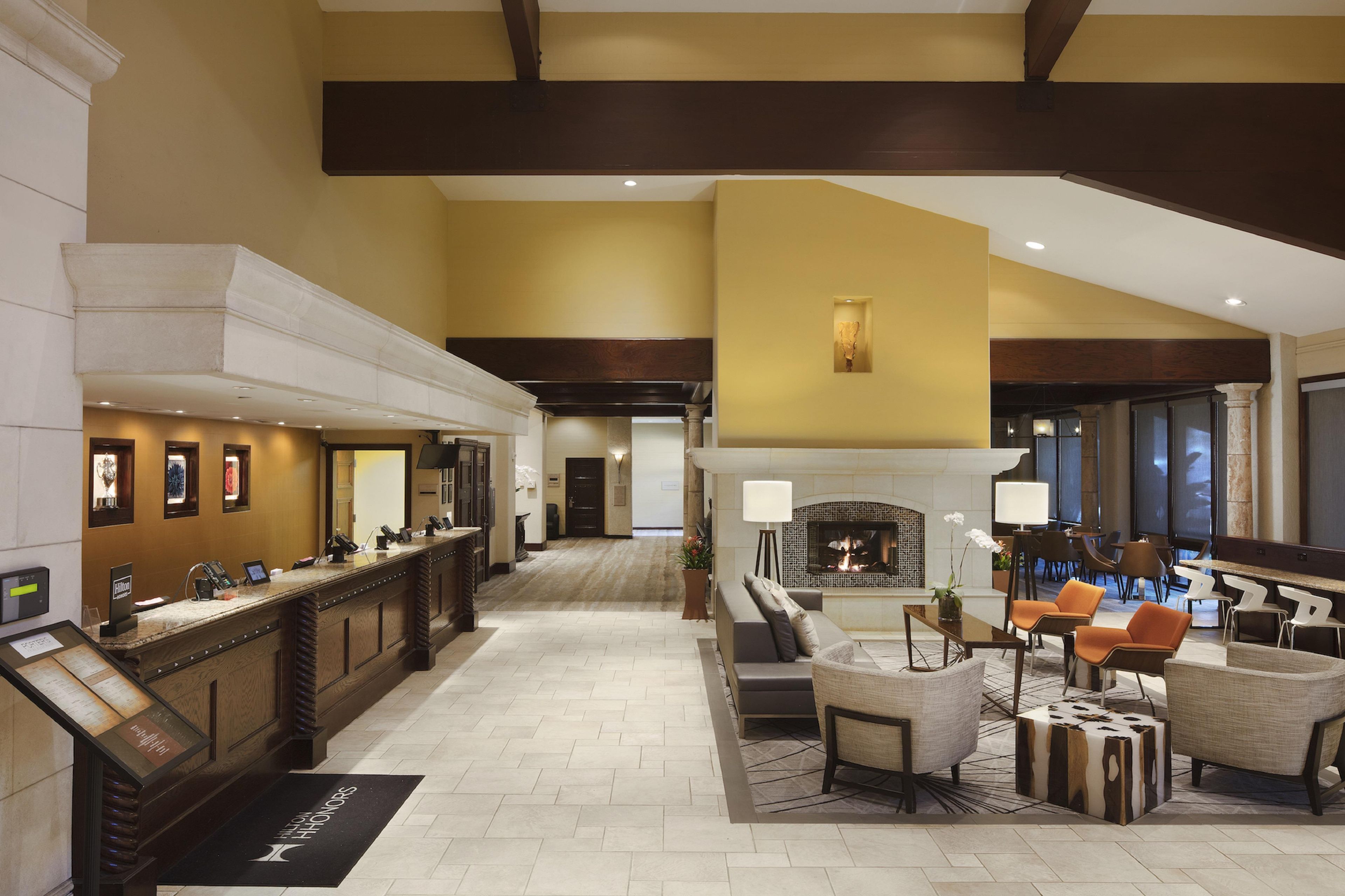 Un hall de hotel con mostrador de recepción, zona de estar y chimenea.