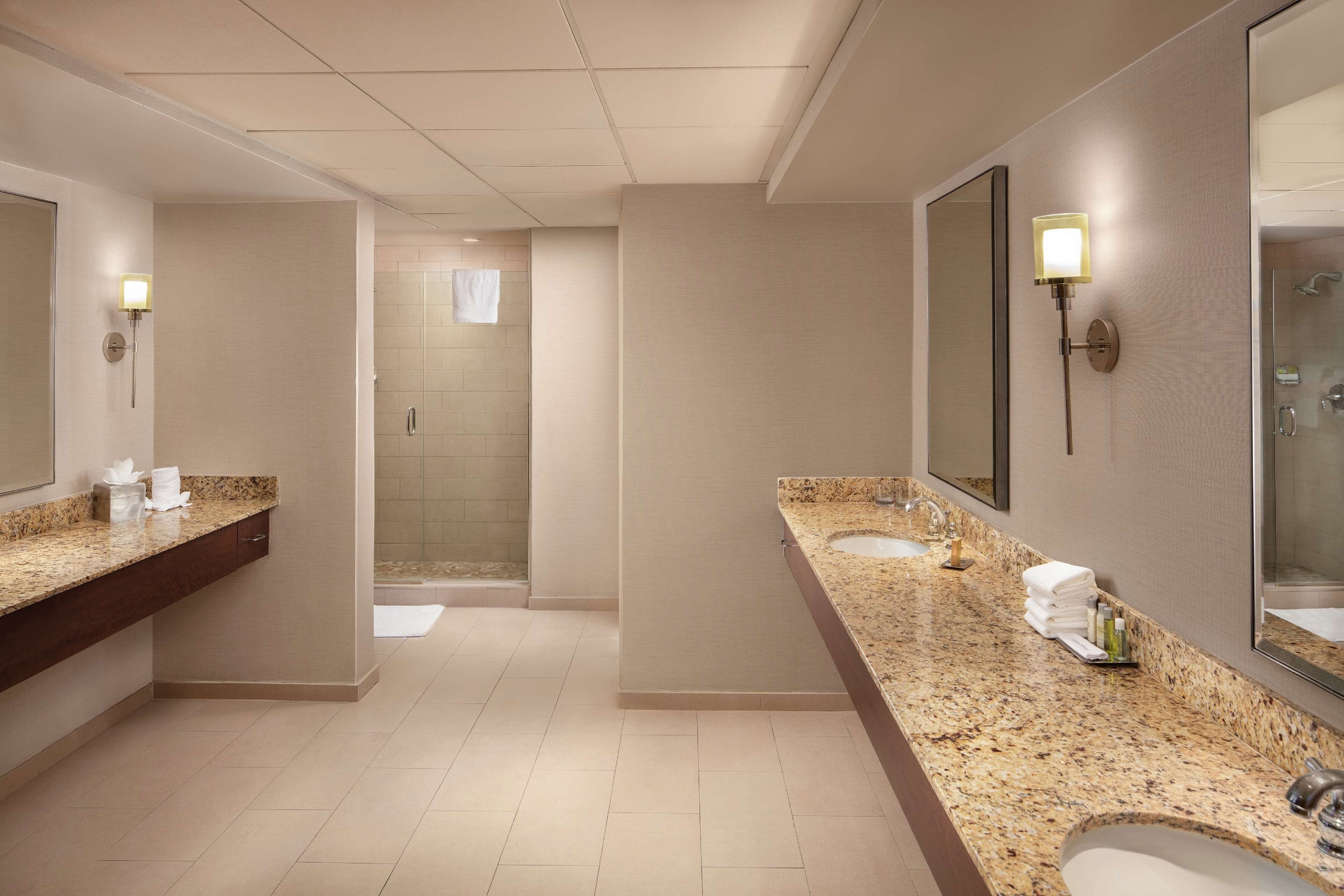 Un baño moderno con dos lavamanos, un espejo grande y una zona de ducha.