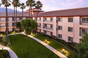 A multi-story hotel with a flat roof, balconies, and a well-maintained lawn.