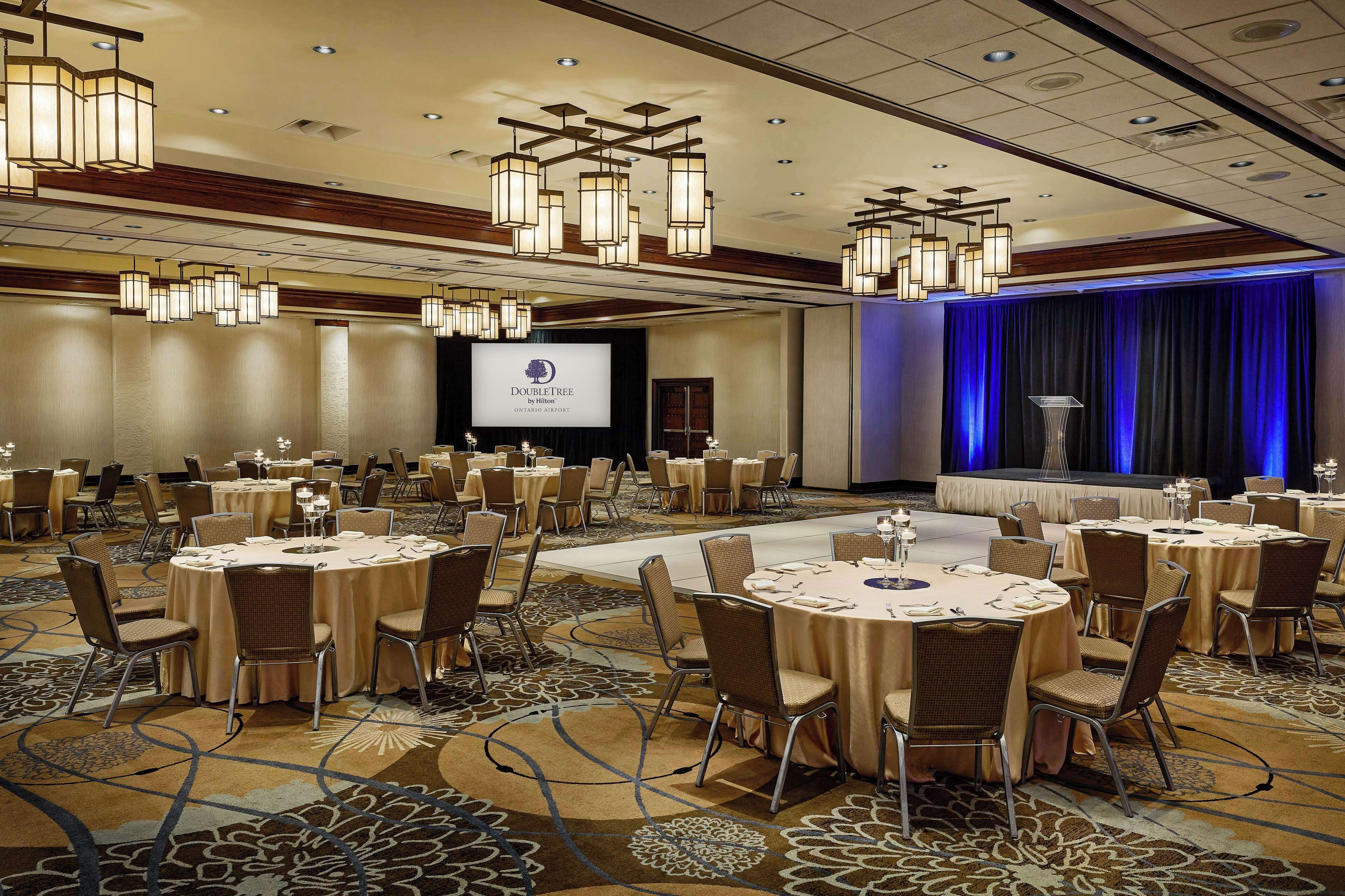 A conference room with round tables, chairs, and a stage with a podium.