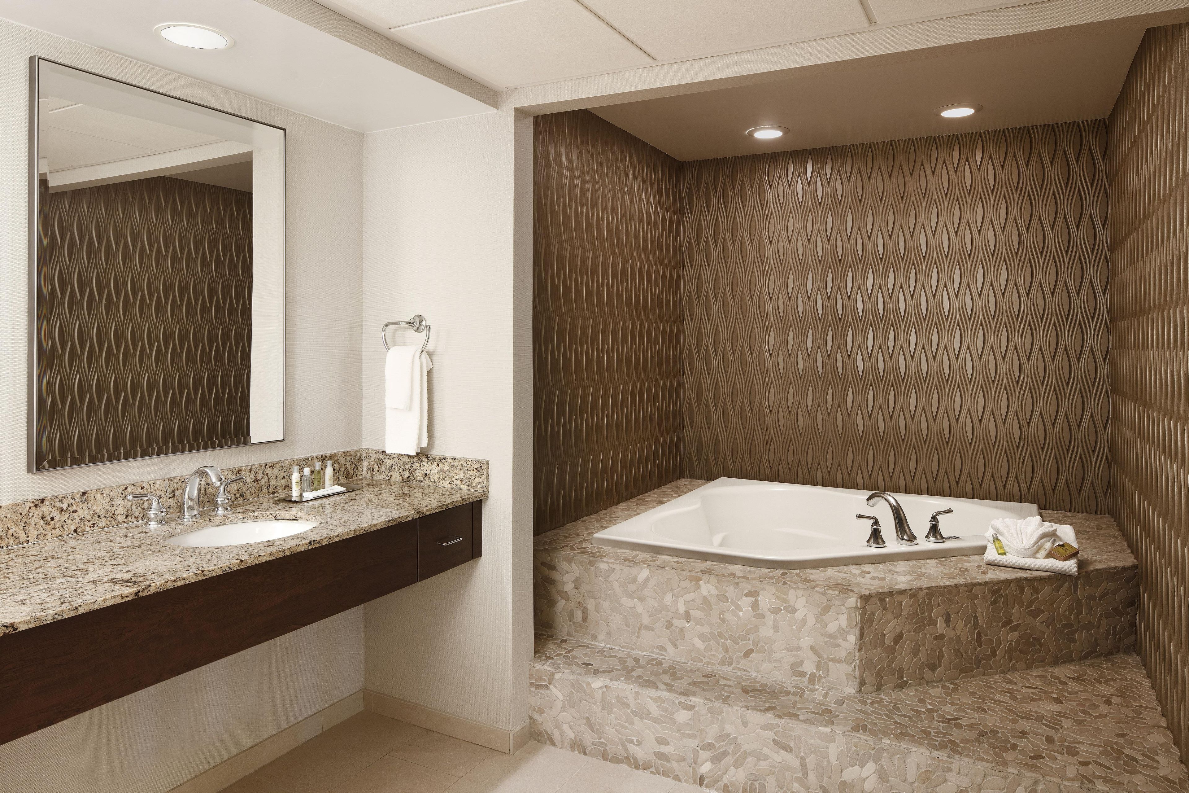 Un baño moderno con un espejo grande, un tocador doble y una bañera independiente.