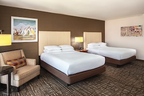 Habitación de hotel con dos camas, un sofá, una mesita y dos lámparas.