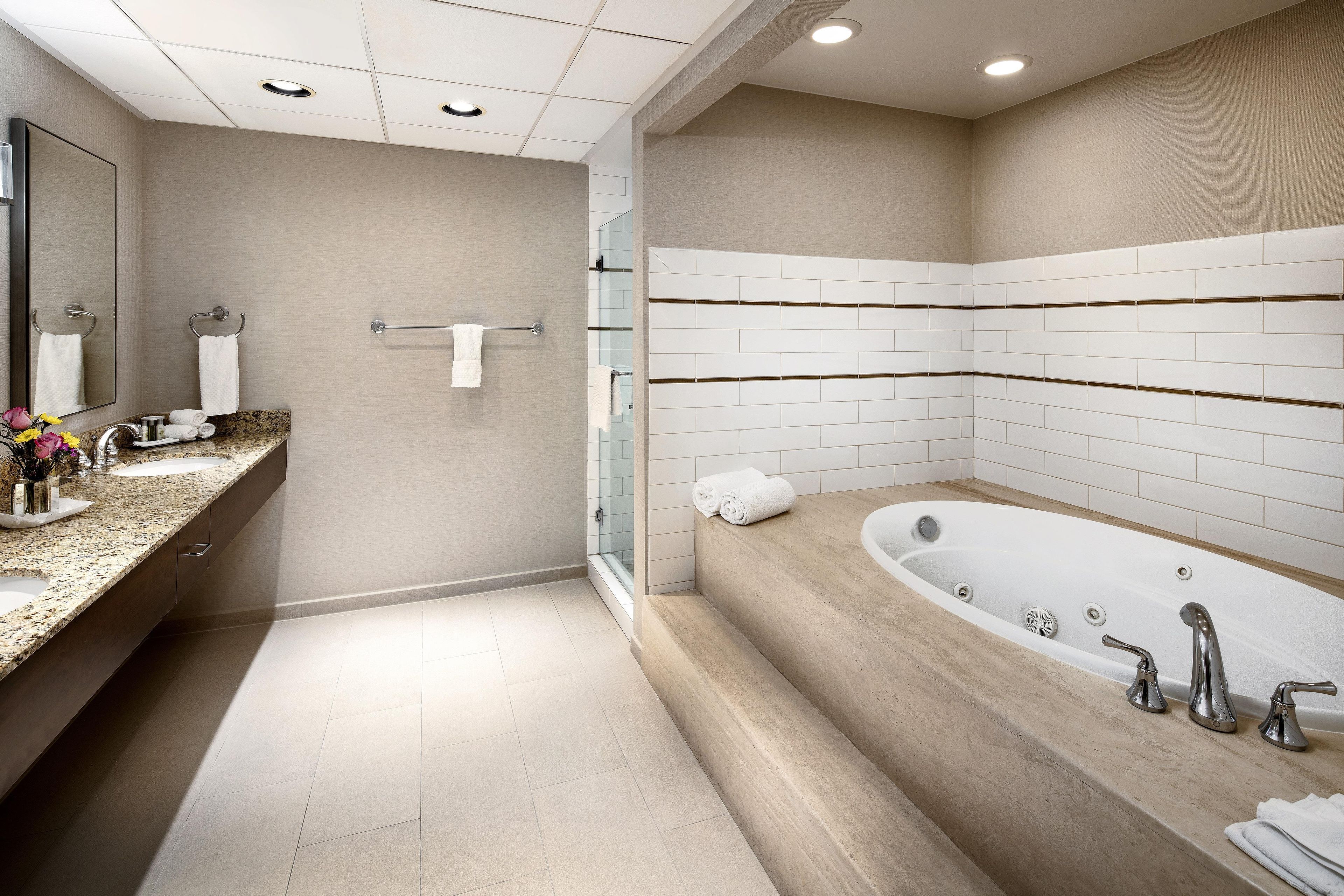 A modern bathroom with a large bathtub, a vanity with a mirror, and a glass shower enclosure.