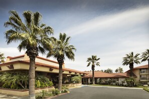 A hotel with a courtyard, palm trees, and a building with a red-tiled roof. - DoubleTree by Hilton Ontario Airport (Ontario)