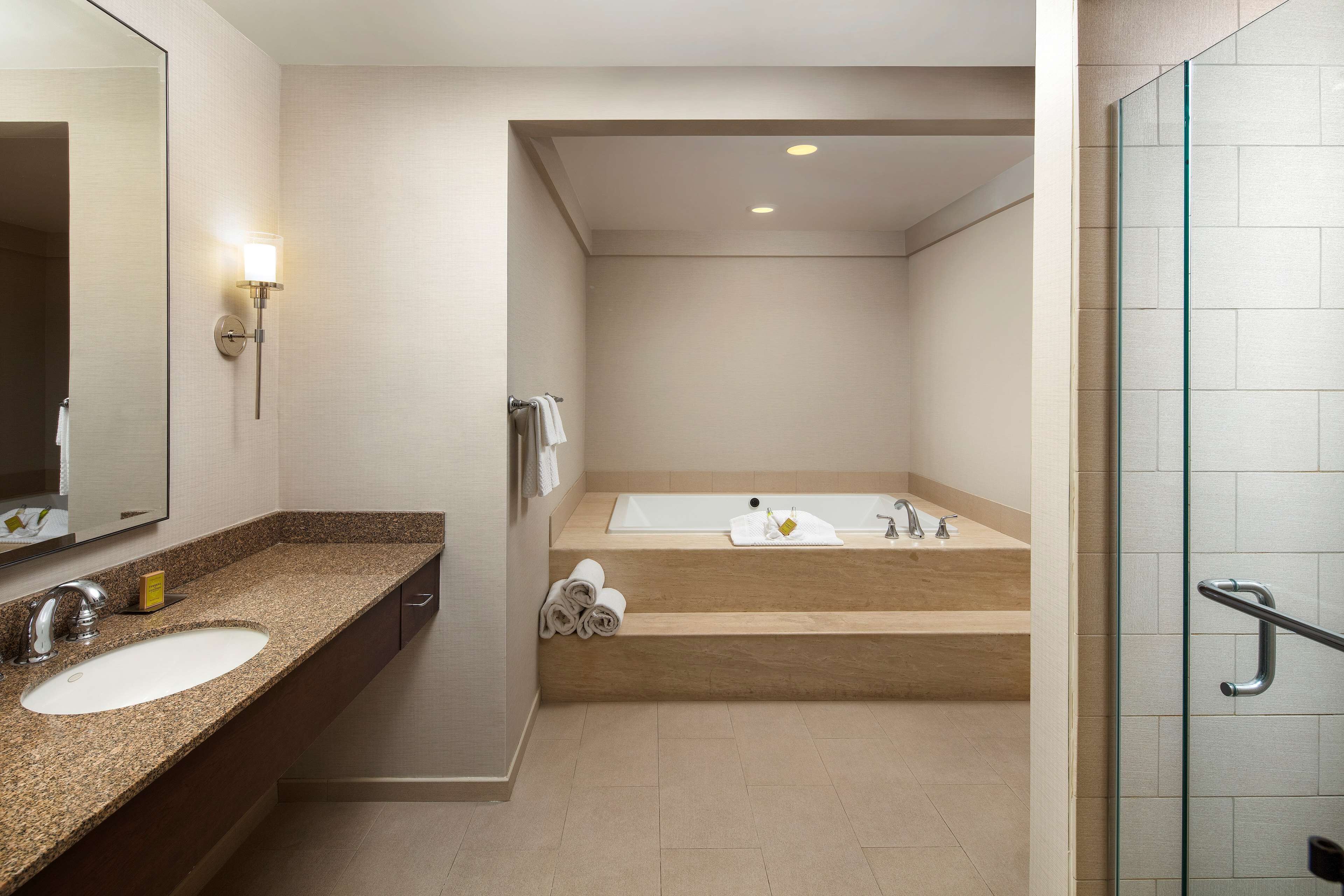 A modern bathroom with two sinks, a bathtub, and a glass shower enclosure.