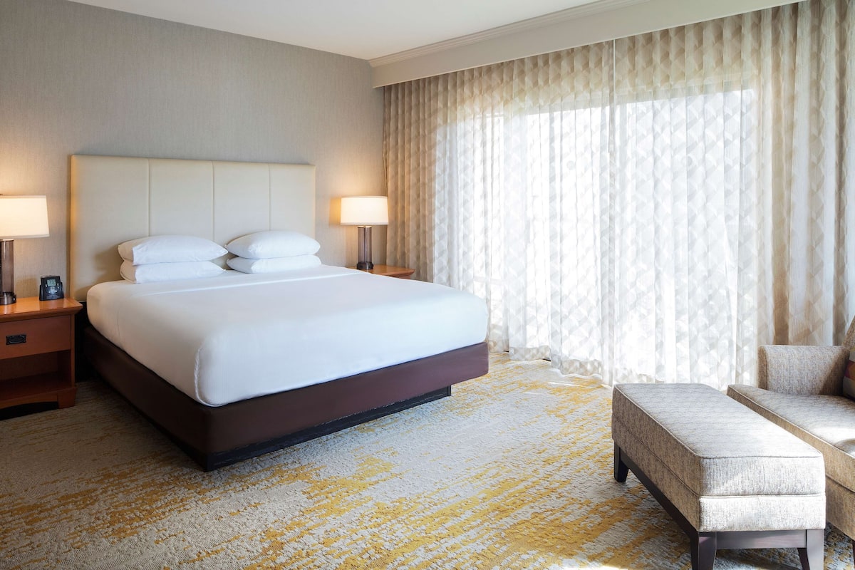 Ein Hotelzimmer mit einem großen Bett, zwei Nachttischen, einer Sitzecke und einem gemusterten Teppich.