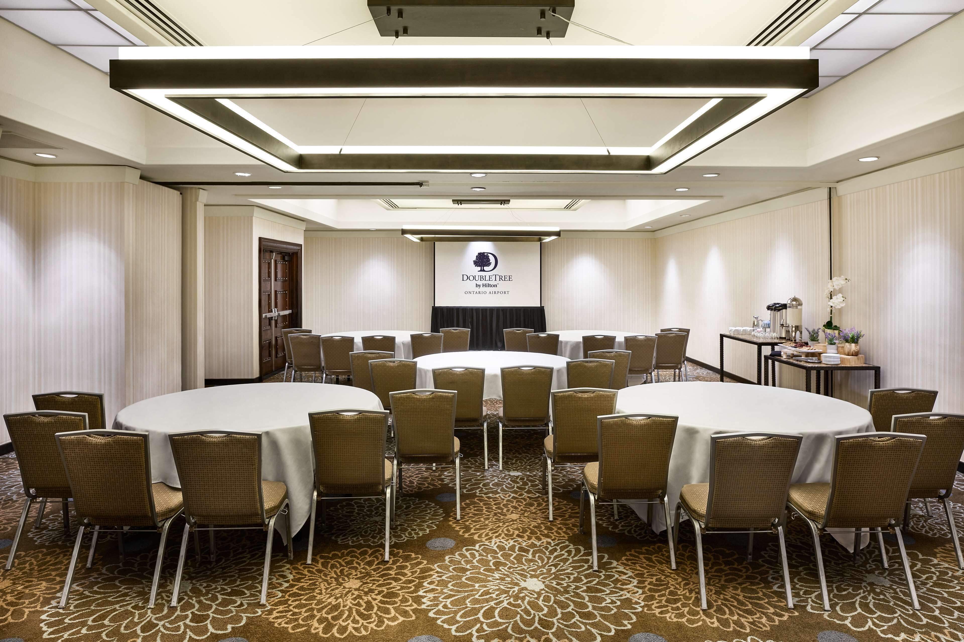 A conference room with a large round table surrounded by chairs, a podium, and a screen displaying the DoubleTree logo.