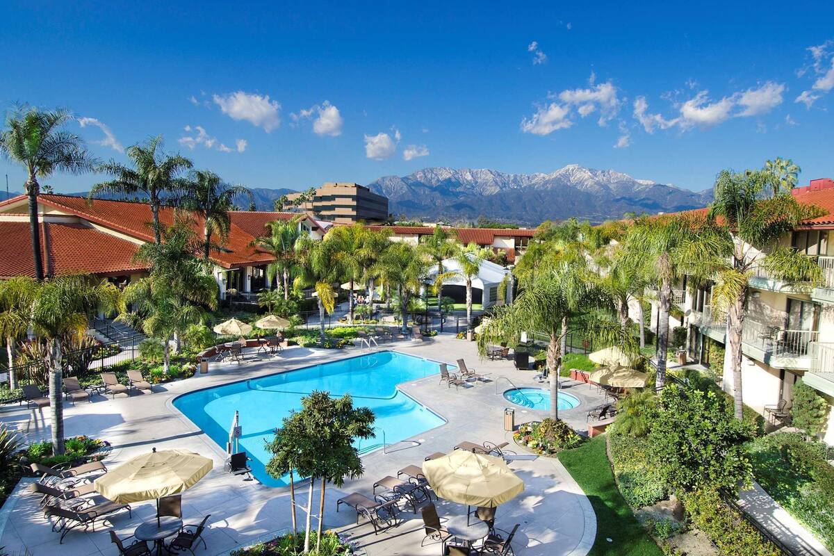 Ein Resort mit großem Pool, Palmen und Bergblick.