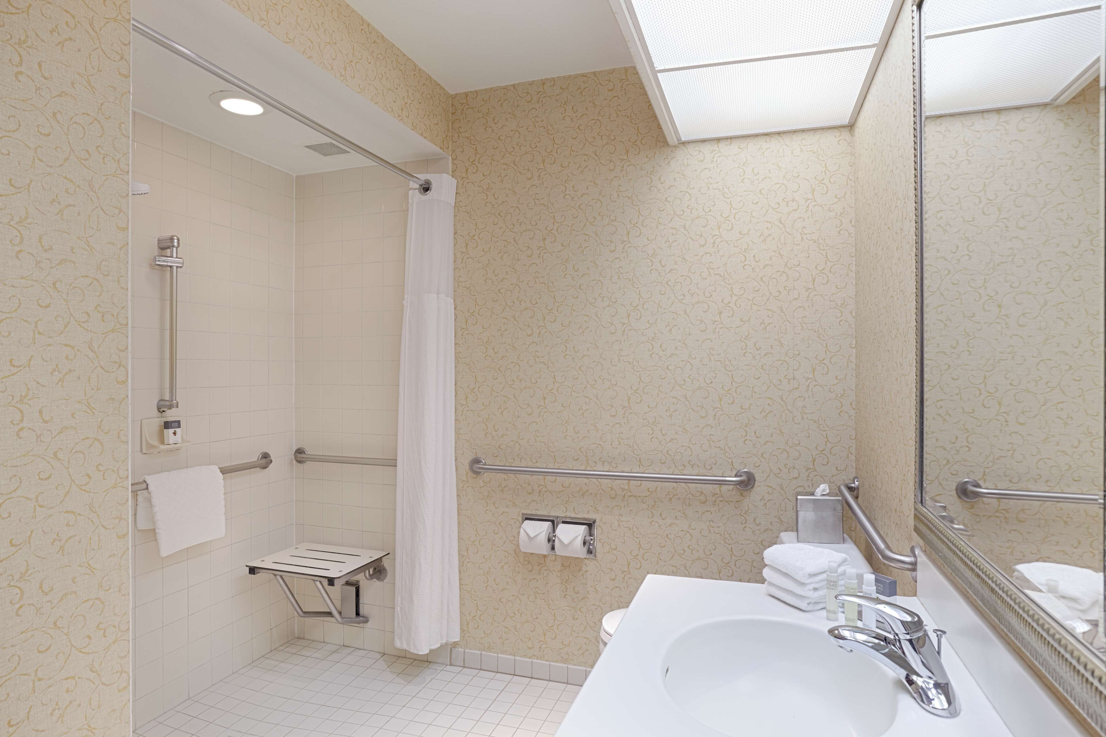 Une salle de bain équipée d’une douche, de toilettes et d’un lavabo, ainsi que de barres d’appui et d’un porte-serviettes.
