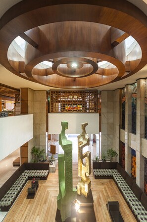Un vestíbulo moderno con techo de madera, una escultura central y zonas de estar.