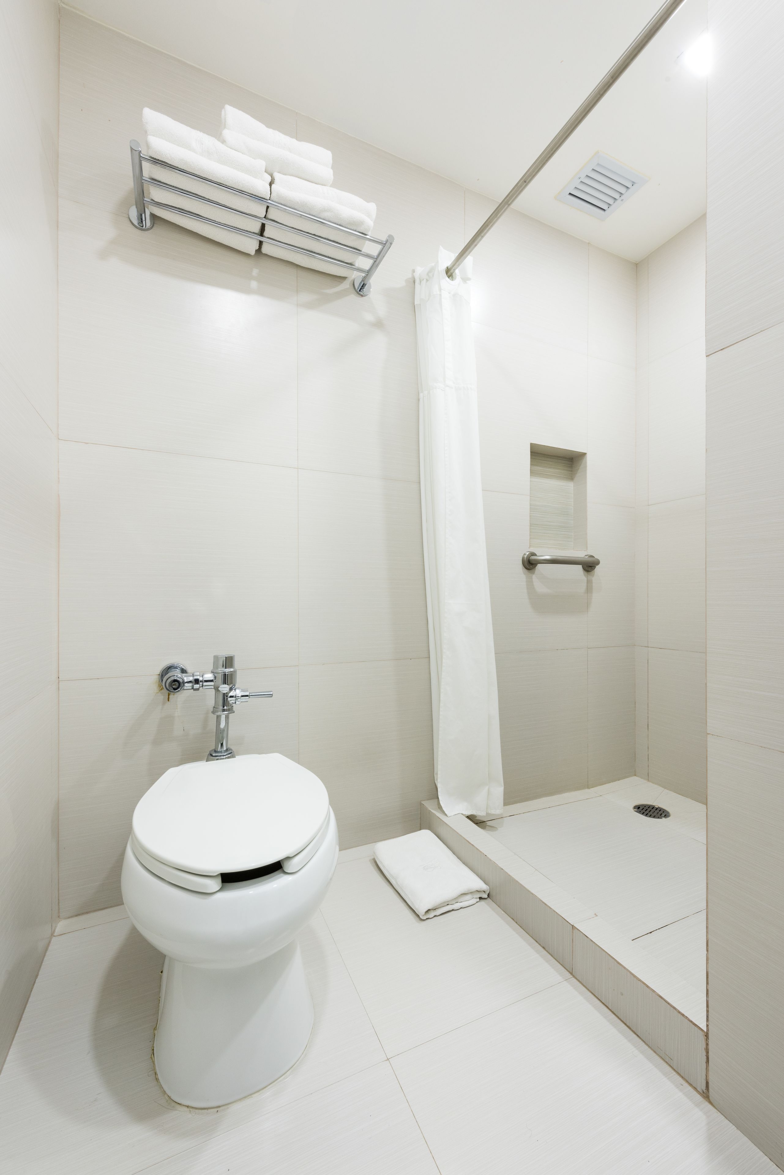 Une salle de bain moderne équipée de toilettes, d’une douche et d’un porte-serviettes.