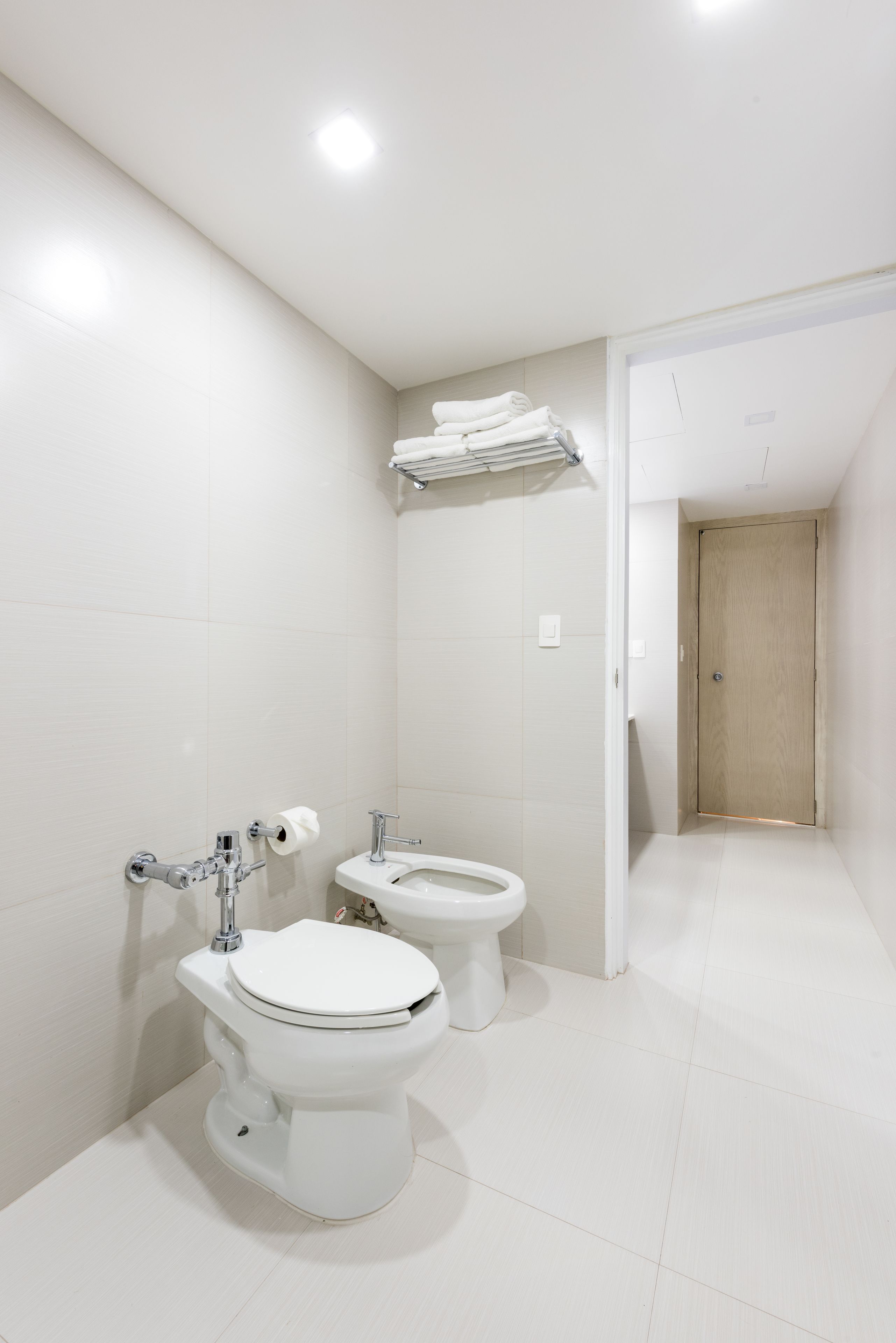 Un baño moderno con dos inodoros, un lavabo y un perchero para toallas.