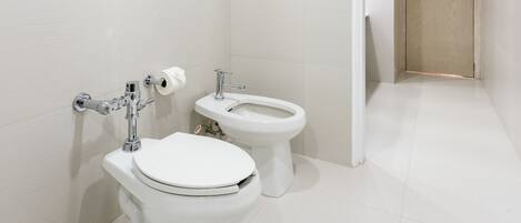 Un baño moderno con dos inodoros, un lavabo y un perchero para toallas.