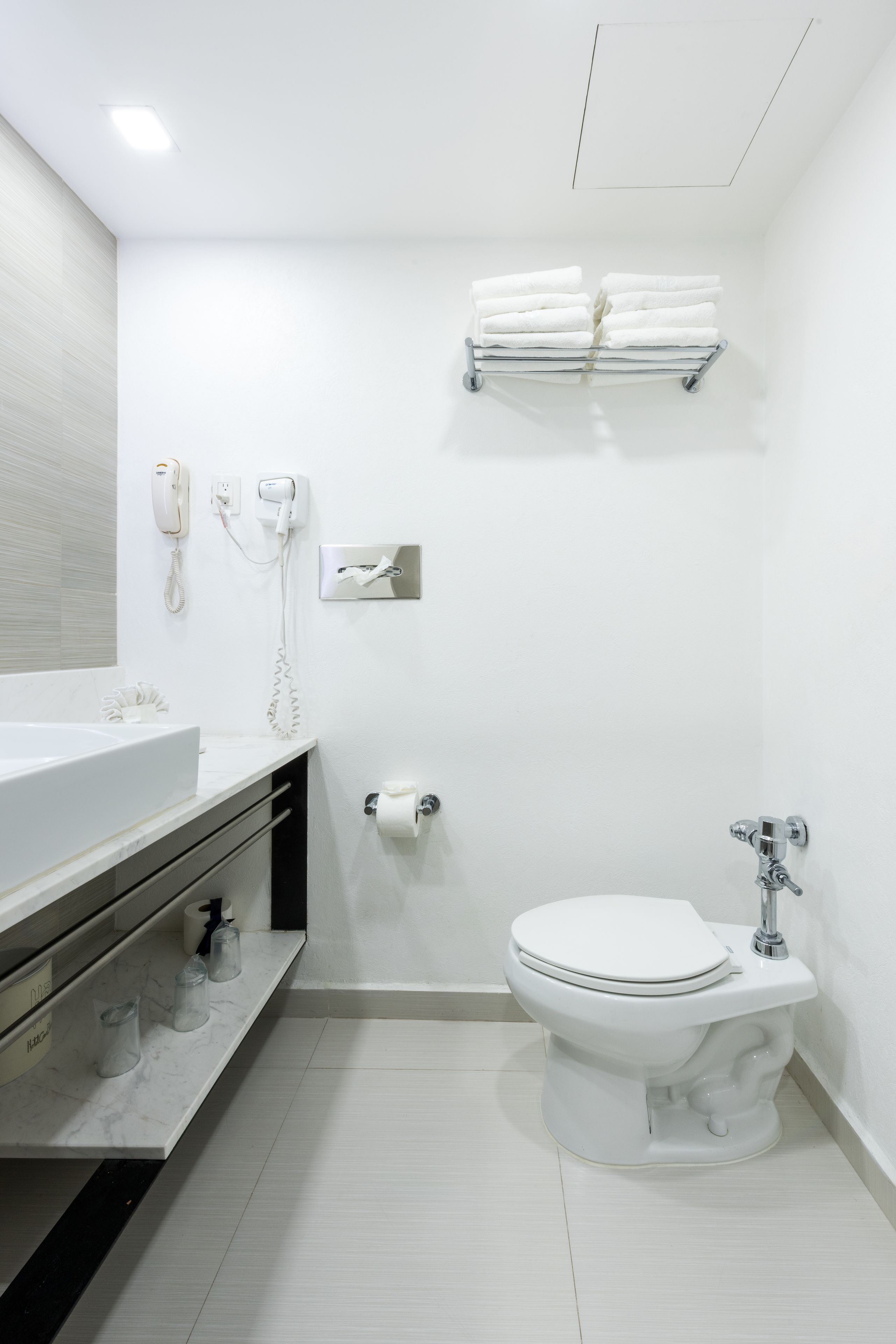 Uma casa de banho moderna com uma pia branca, sanita e barra para toalhas.