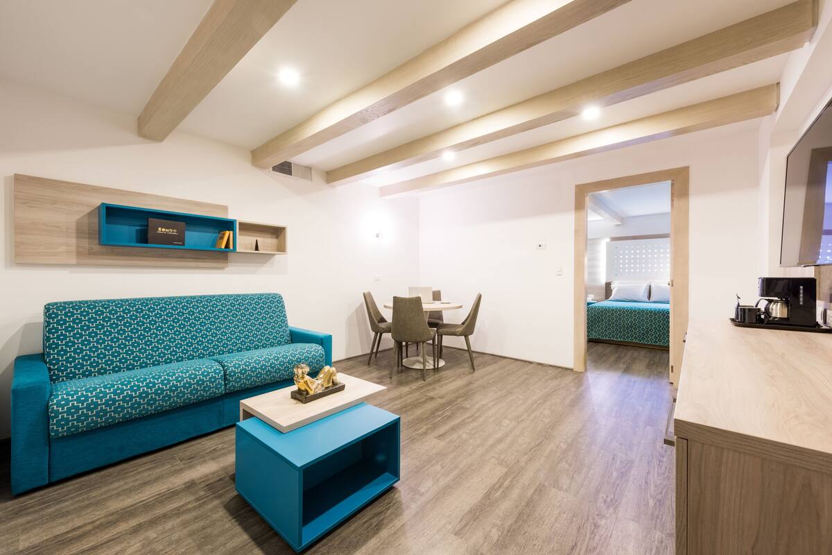 Una sala de estar moderna con un sofá azul, una mesa de centro y un comedor con sillas y una mesa.