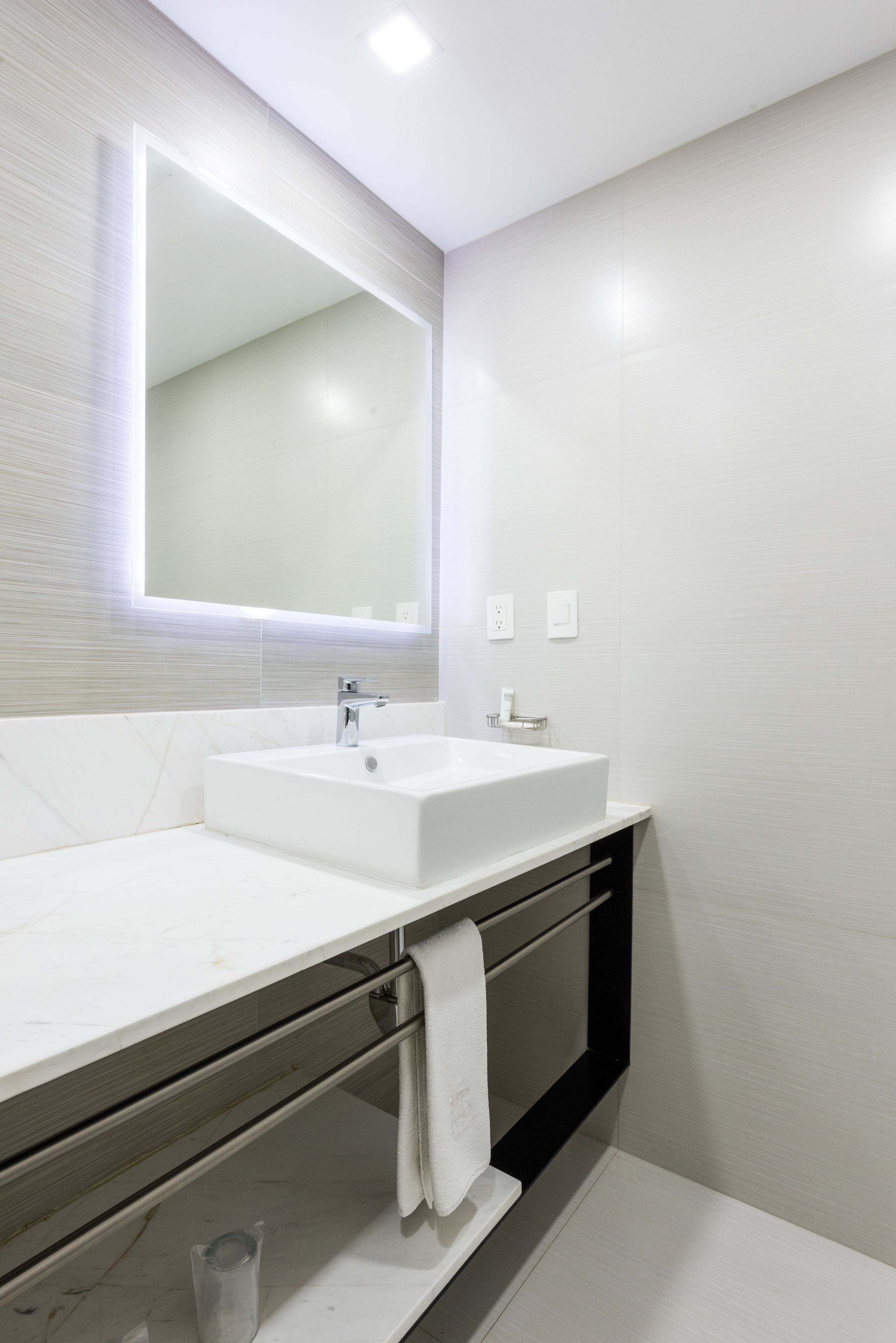 Un baño moderno con un espejo grande, dos lavabos y un perchero para toallas.