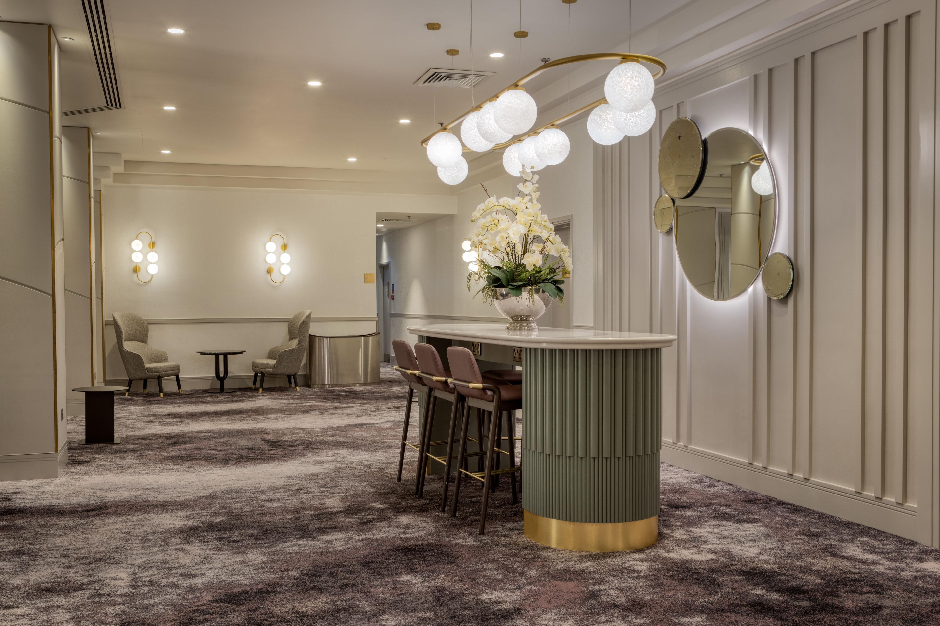 A hotel lobby with a bar area, seating, and a decorative light fixture.