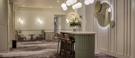 A hotel lobby with a bar area, seating, and a decorative light fixture.