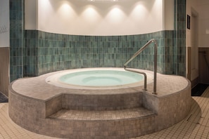 A circular hot tub with a metal ladder, surrounded by a tiled floor and walls. - Hilton Glasgow (Glasgow)