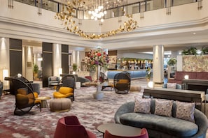 A spacious lobby with a bar area, seating arrangements, and a decorative chandelier. - Hilton Glasgow (Glasgow)