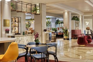 A modern hotel lobby with a coffee bar, seating areas, and a reception desk. - Hilton Glasgow (Glasgow)