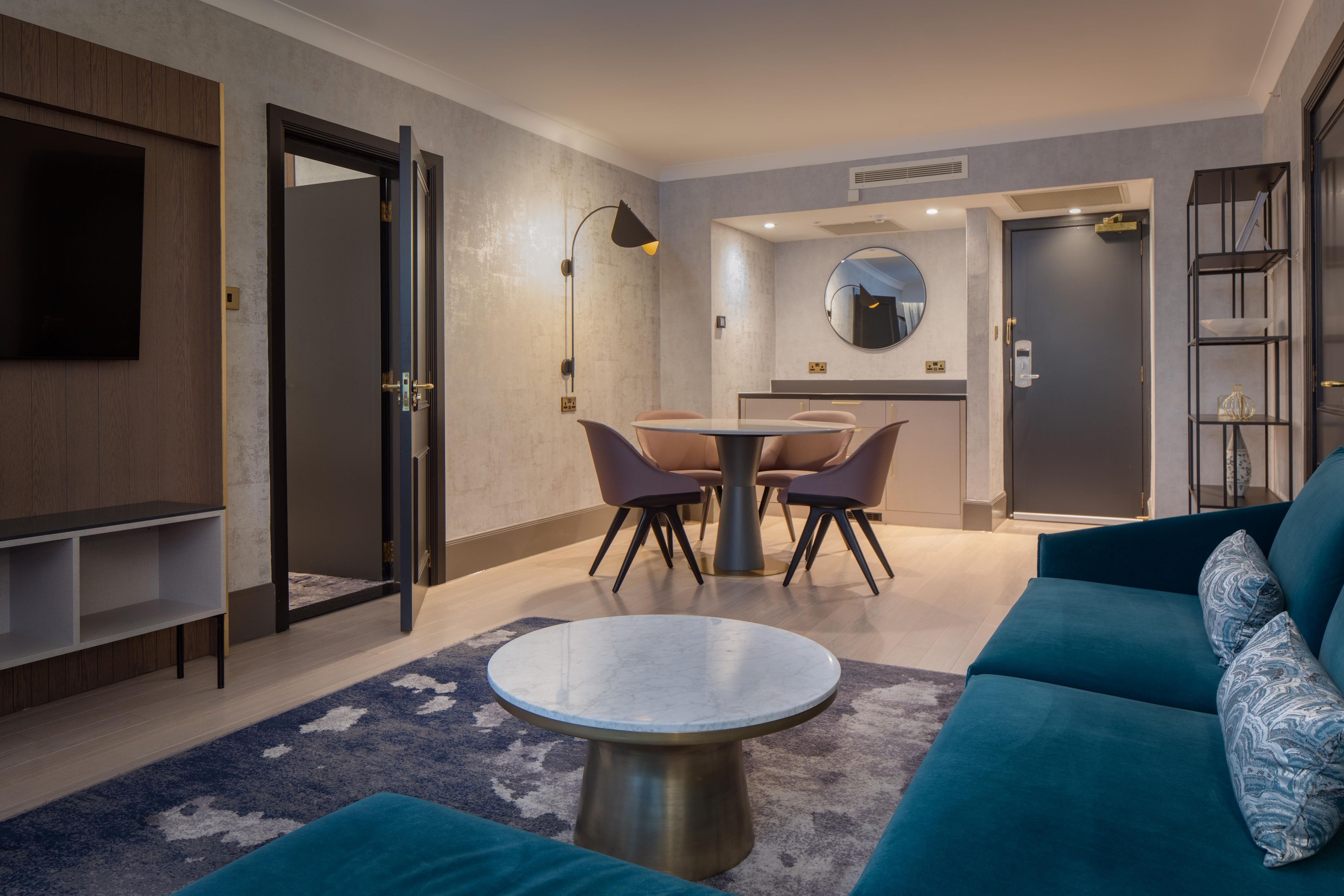 A modern living room with a sofa, a round coffee table, and a dining area with chairs and a table.
