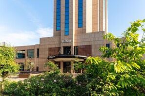 A Hilton hotel with a modern design, featuring a prominent entrance and lush greenery in the foreground. - Hilton Glasgow (Glasgow)