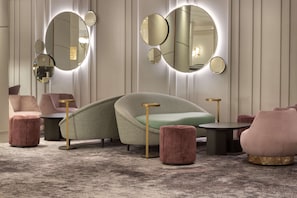 Relax in style with a curved sofa, round mirrors, and plush ottomans.