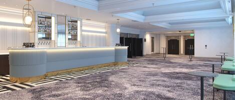A modern hotel lobby with a reception desk, seating area, and a staircase.
